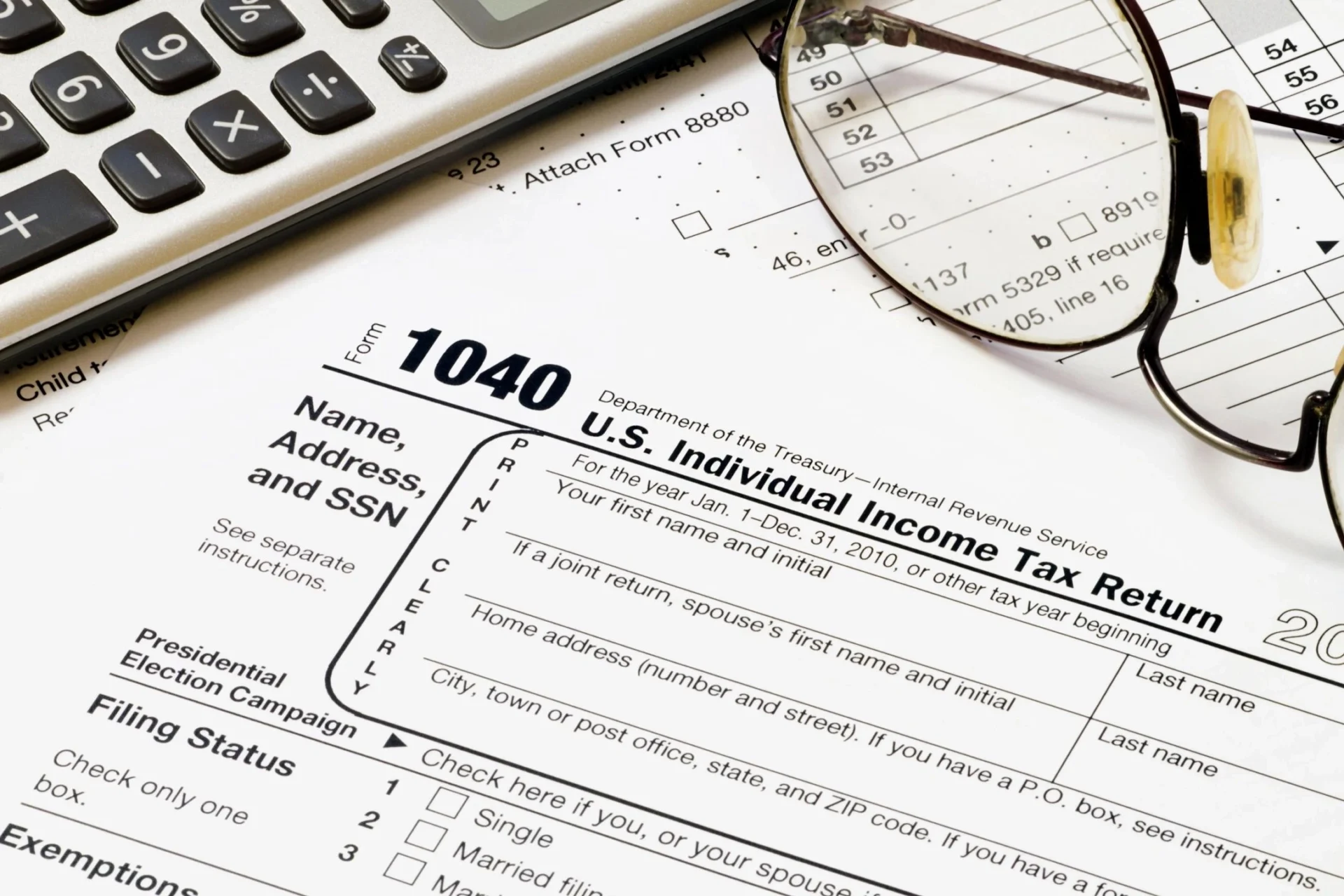 An individual income tax return form, a calculator, and a pair of glasses